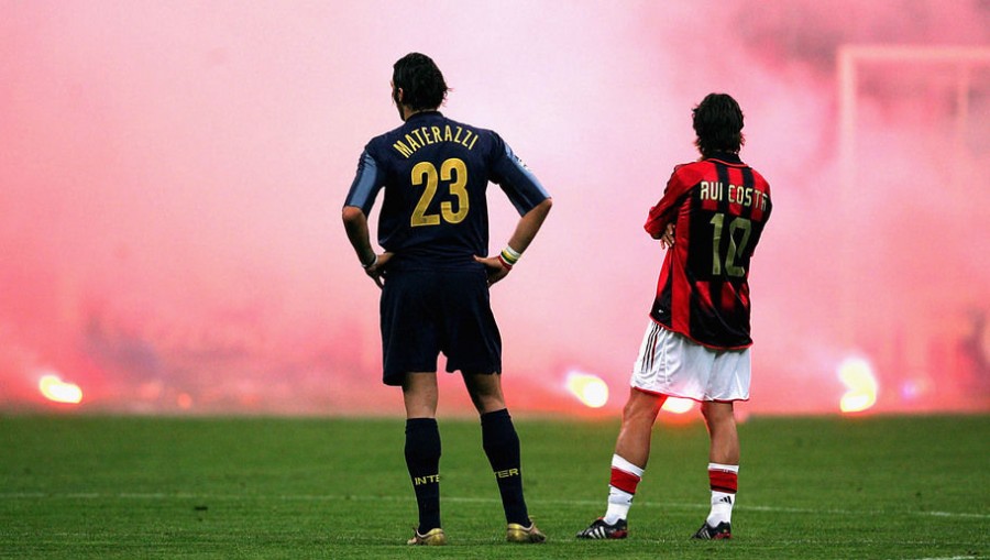 MILAN, ITALY -  APRIL 12:  Marco Materazzi of Inter Milan and Rui Costa of AC Milan look on as Inter fans shower the pitch with flares during the UEFA Champions League quarter-final second leg between AC Milan and Inter Milan at the San Siro Stadium on April 12, 2005  in Milan, Italy. (Photo by Mike Hewitt/Getty Images)